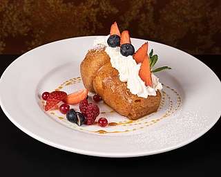 Dolce decorato con panna, fragole e mirtilli su piatto bianco.