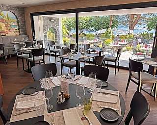 Innenansicht eines Restaurants mit Blick auf den See und eine malerische Wandmalerei.