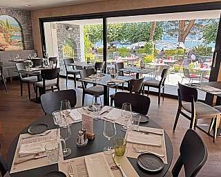 Interno di un ristorante con vista sul lago e tavoli apparecchiati.