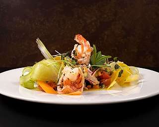 Piatto di insalata con gamberi, verdure e erbe fresche.