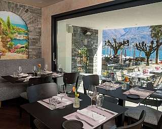 Interno di un ristorante con vista sul lago e tavoli apparecchiati.