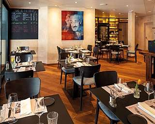 Innenansicht eines Restaurants mit Tischen und einer Wandtafel.