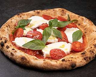 Eine Pizza mit frischem Mozzarella, Kirschtomaten und Basilikum.