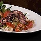 Polpo grigliato servito con insalata e agrumi freschi.