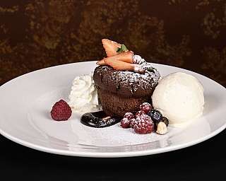 Tortino al cioccolato con panna, gelato e frutti di bosco.